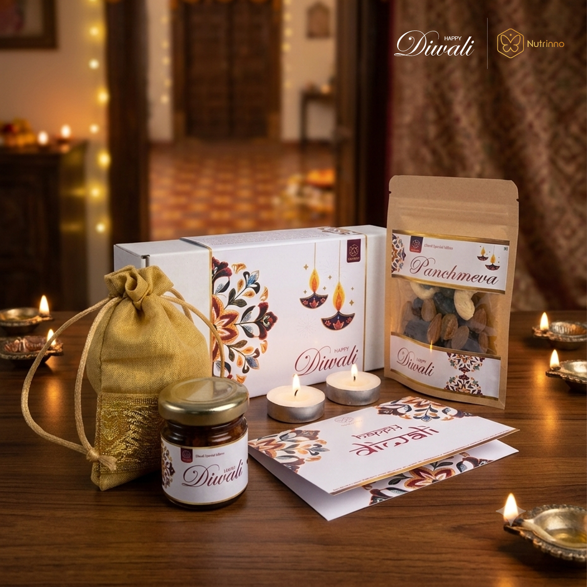 Diwali Mini Gift Hamper with a white floral-patterned gift box, brown nut pouch, jar, golden fabric bag, candles and greeting card.